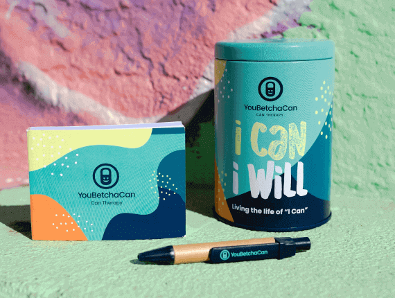 A tin can with beautiful colors with a note pad and a pen to help you set goals for your life.